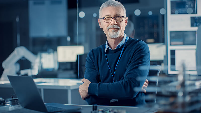 Man with crossed arms in front of a computer, representing experience and value in business
